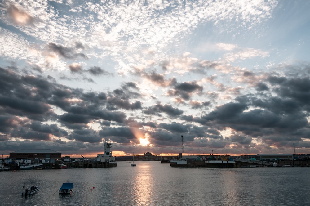 a body of water with boats on it under a cloudy sky