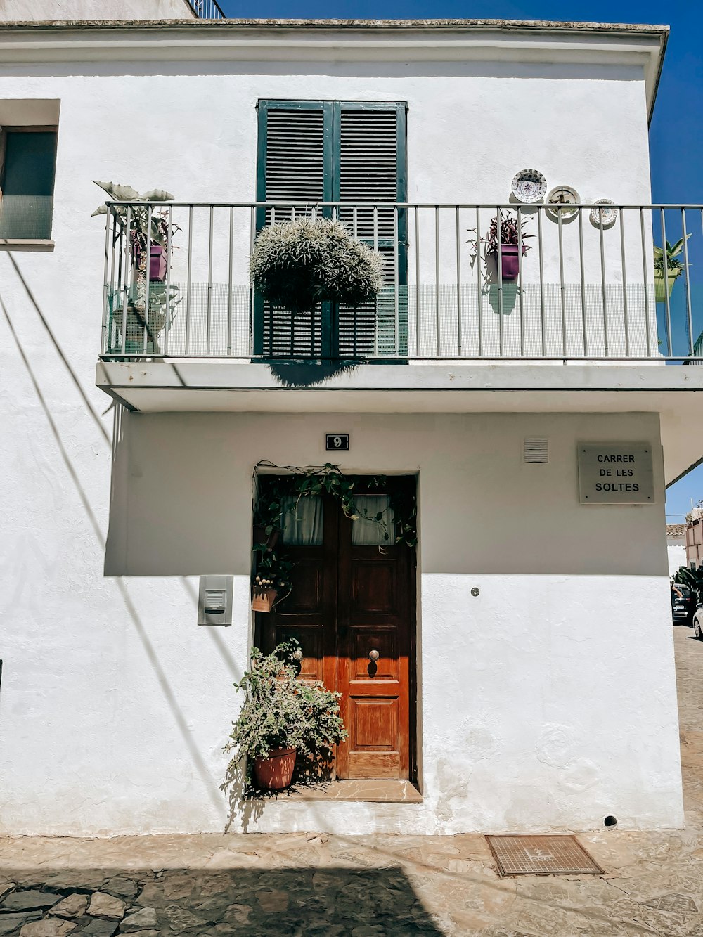 a white building with a balcony and a wooden door