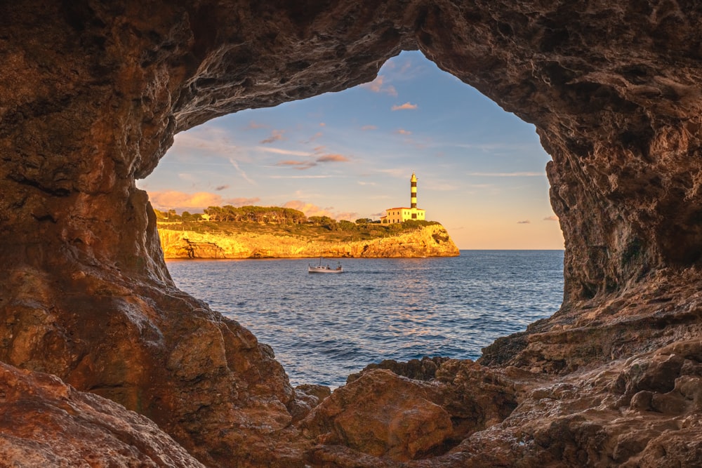 a view of a lighthouse through a cave