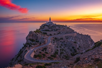a Formentor lighthouse on top of a hill near the ocean