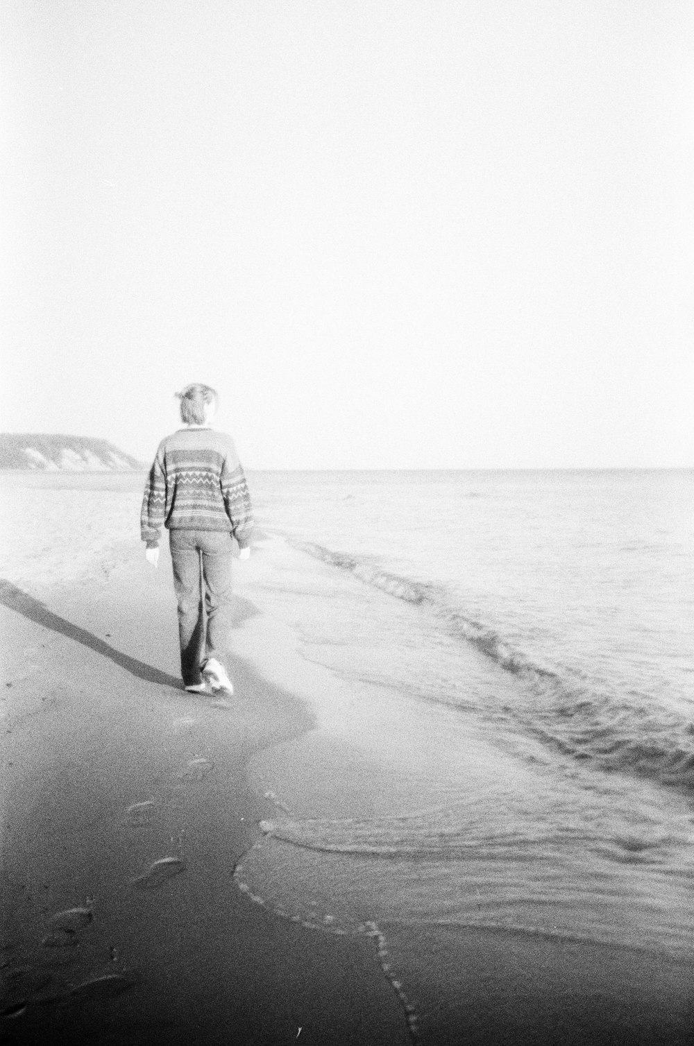 a man walking along a beach next to the ocean