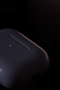 Close-up of a sleek wireless device glowing softly in a dark room.