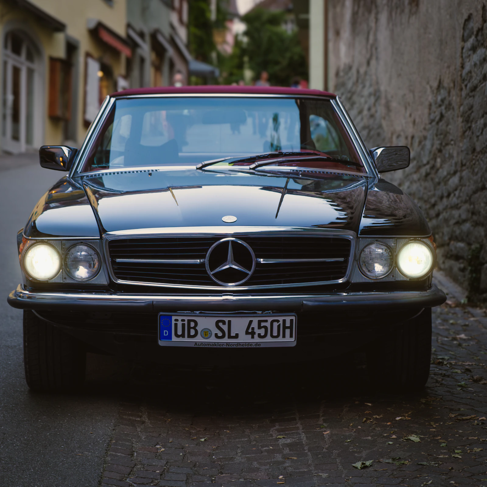 Mercedes-Benz SL der Baureihe R107 mit eingeschalteten Scheinwerfern
