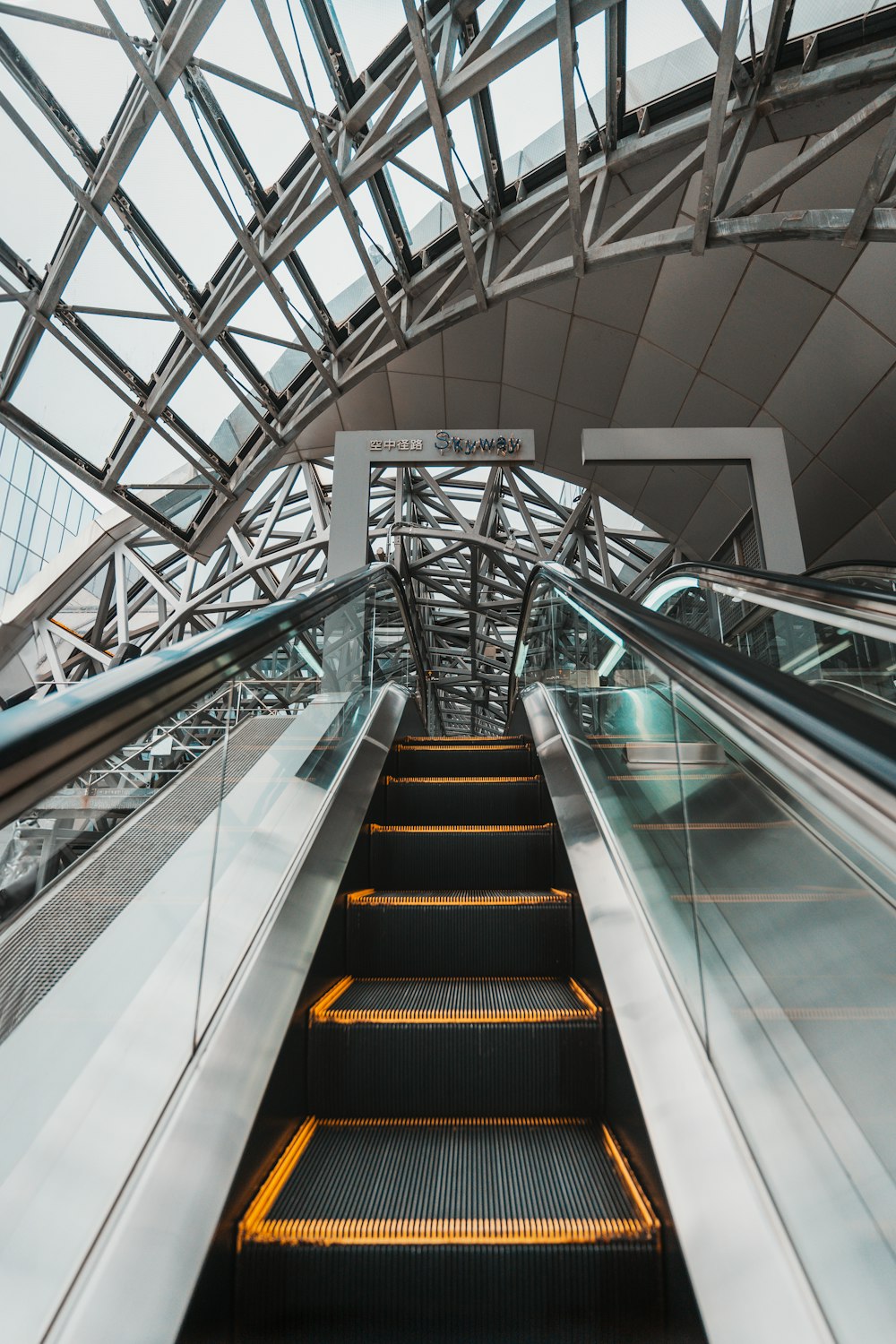 an escalator in a building with a glass ceiling