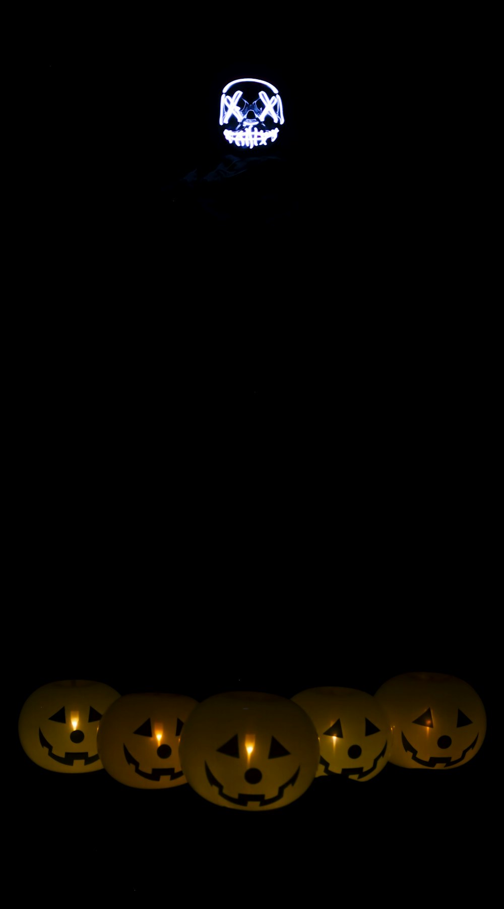 a row of jack o lantern pumpkins lit up in the dark