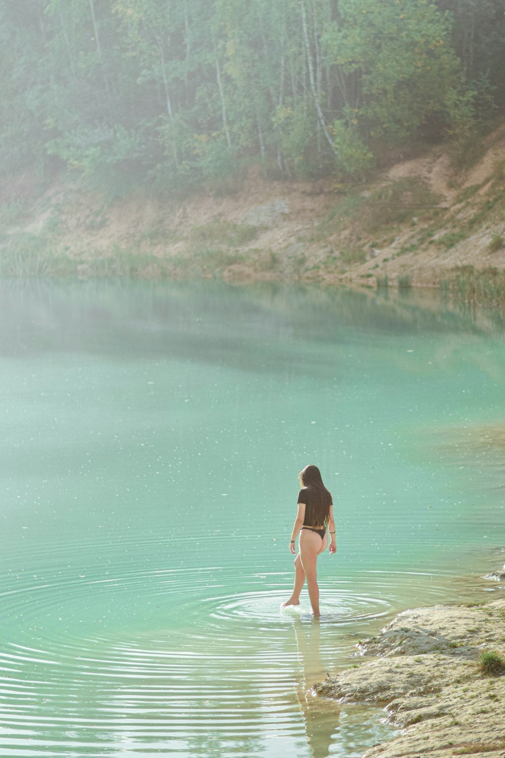 a woman standing in the water of a lake