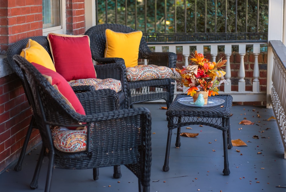 a couple of wicker chairs sitting on top of a porch