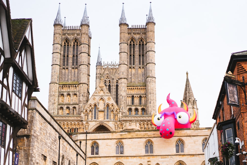 un gran edificio con un monstruo rosa gigante en la parte superior