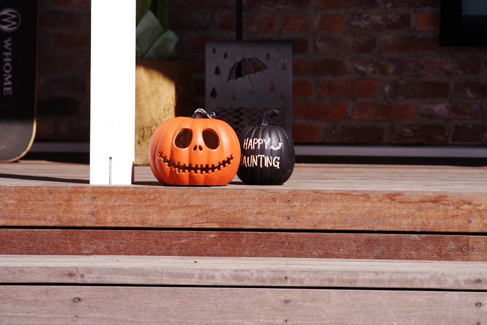 a couple of pumpkins sitting on top of a wooden porch