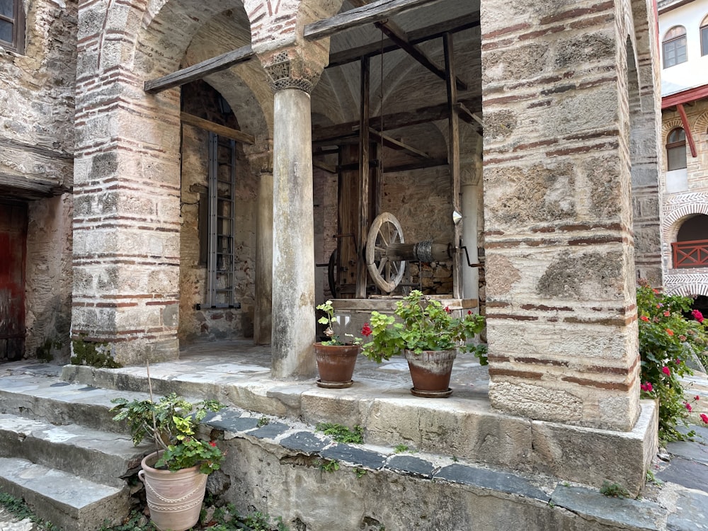 a stone building with potted plants on the steps