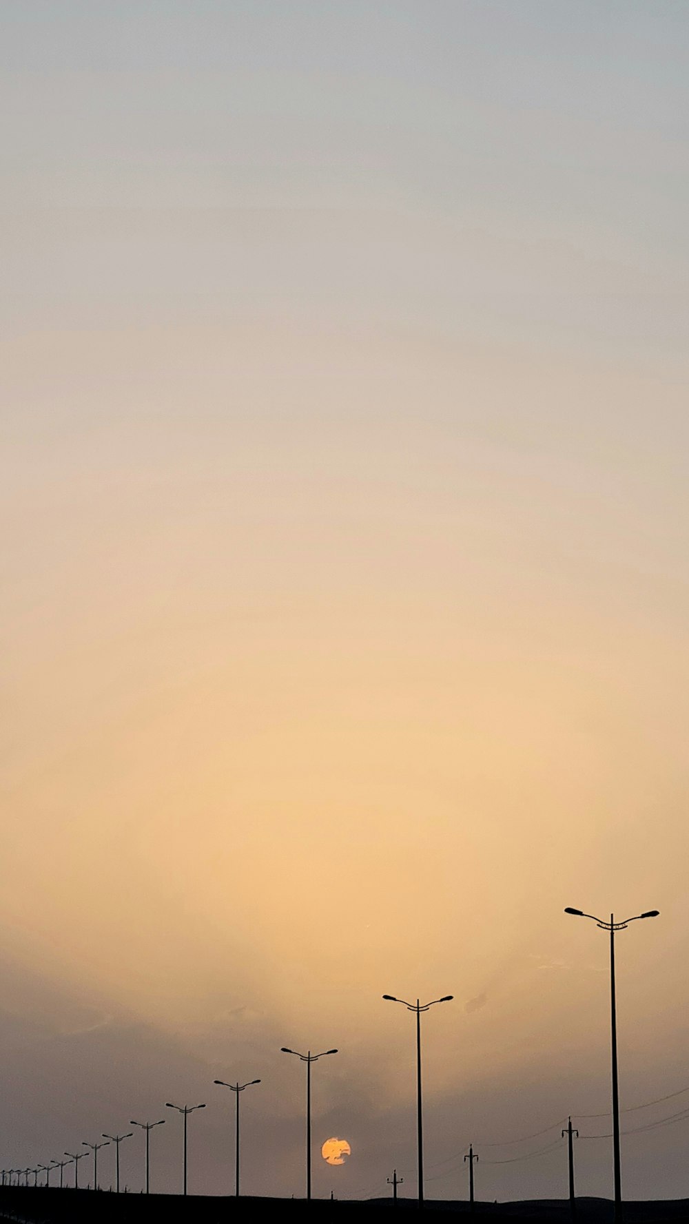 the sun is setting behind a row of street lights