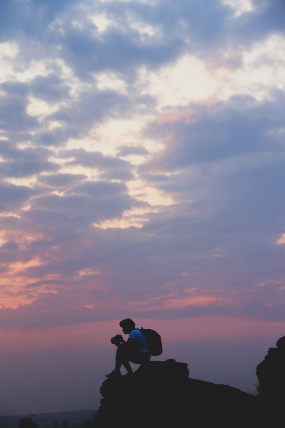 a person with a backpack standing on top of a rock