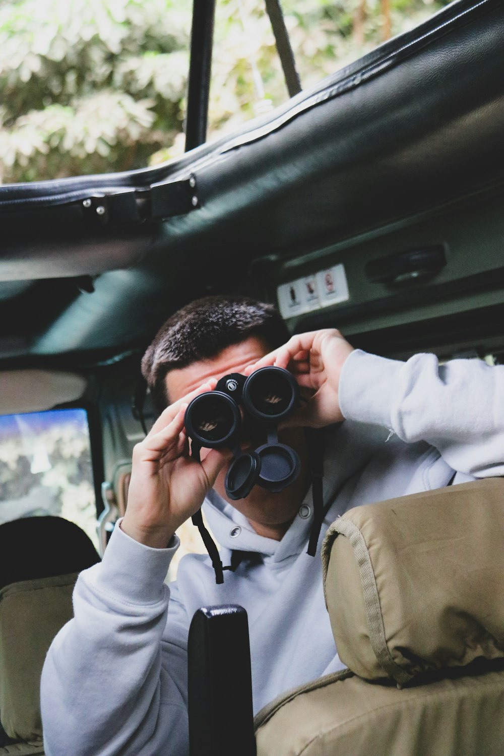 a man sitting in the back of a bus looking through binoculars