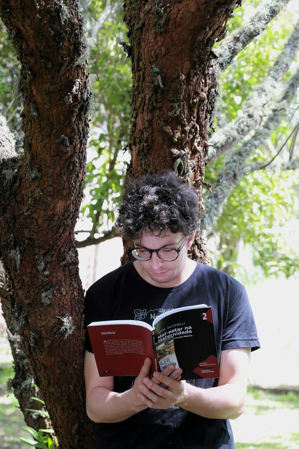 a young man reading a book under a tree