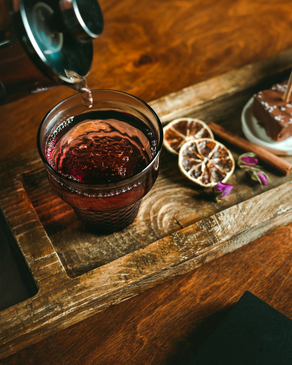 a glass filled with liquid sitting on top of a wooden table