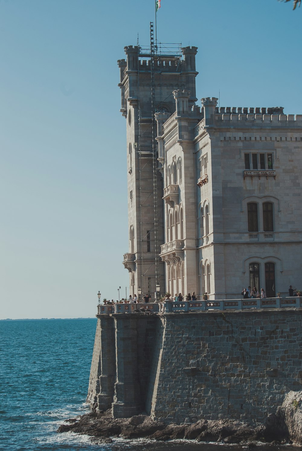 ein hohes Gebäude, das auf einer Klippe neben dem Meer sitzt