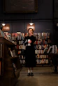 A thoughtful woman reading a book in a cozy library corner filled with warm light.