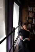 A woman reading a book in a cozy corner of a library.
