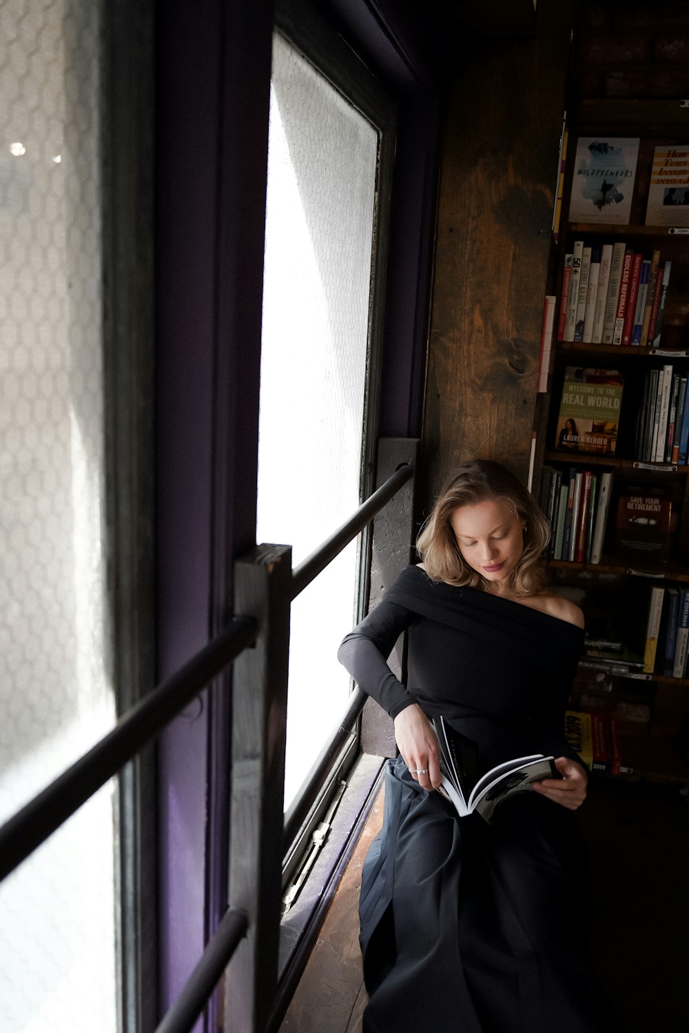 a woman in a black dress reading a book