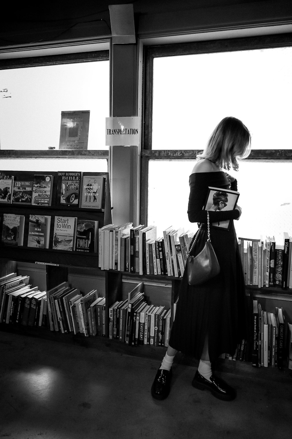 a woman standing in front of a book shelf filled with books