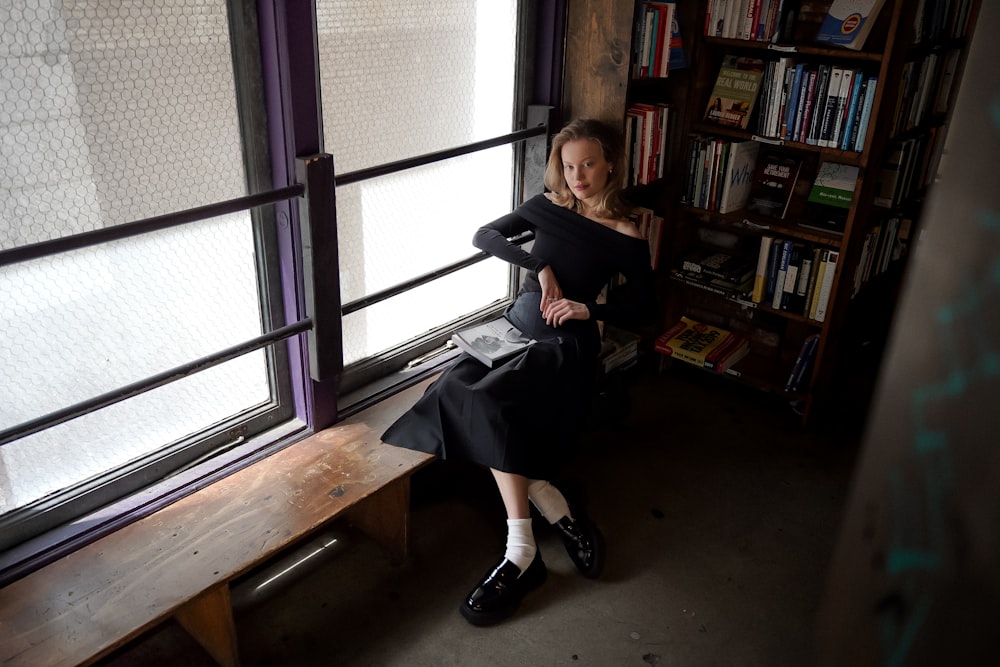 a woman sitting on a bench in front of a window