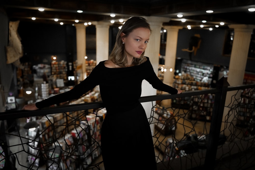 a woman in a black dress standing on a balcony