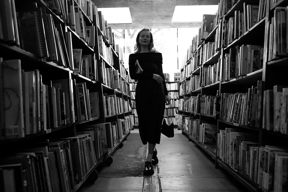 a woman is walking through a library full of books