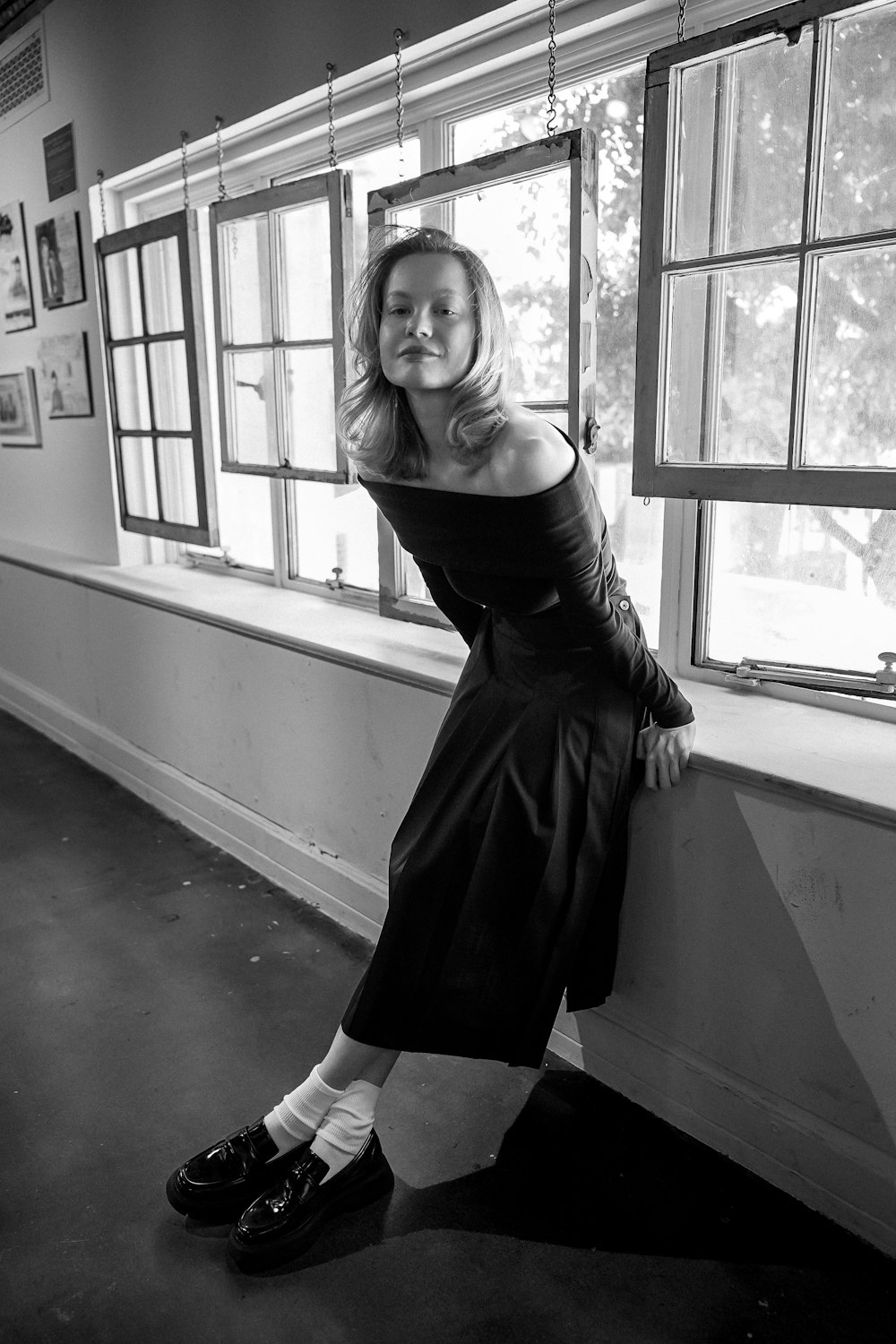 a black and white photo of a woman leaning against a wall