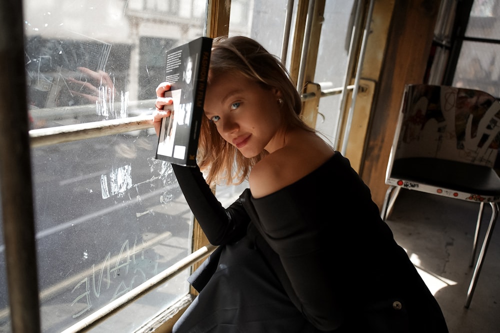 a woman looking out of a window holding a tablet