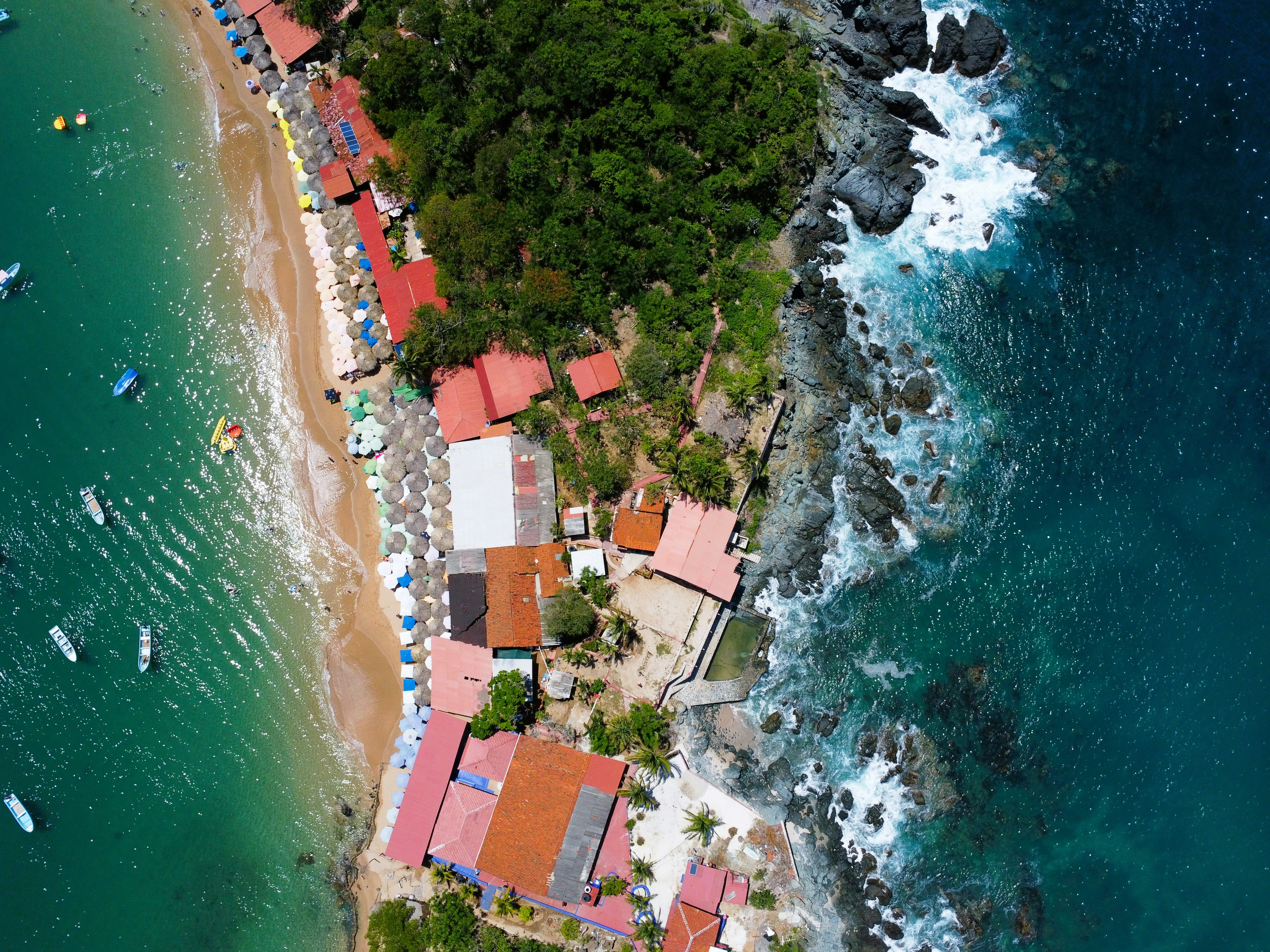 an aerial view of a beach with boats in the water