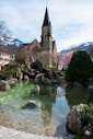 a church with a steeple next to a body of water