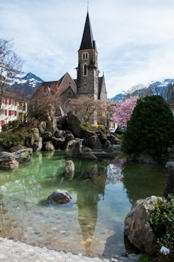 a church with a steeple next to a body of water