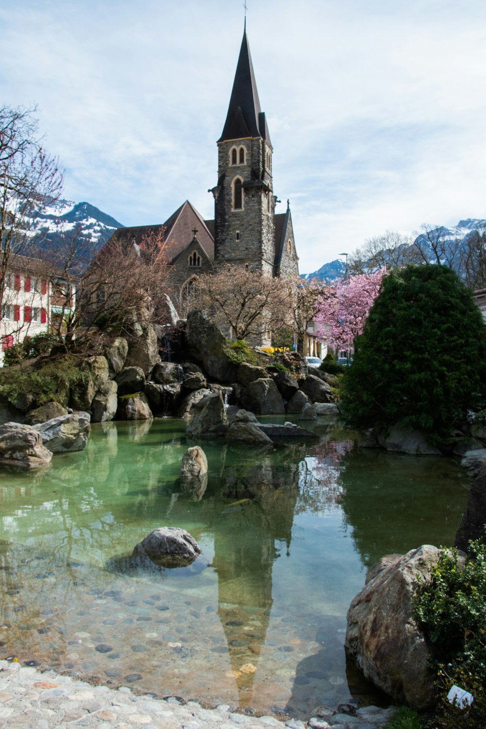 a church with a steeple next to a body of water