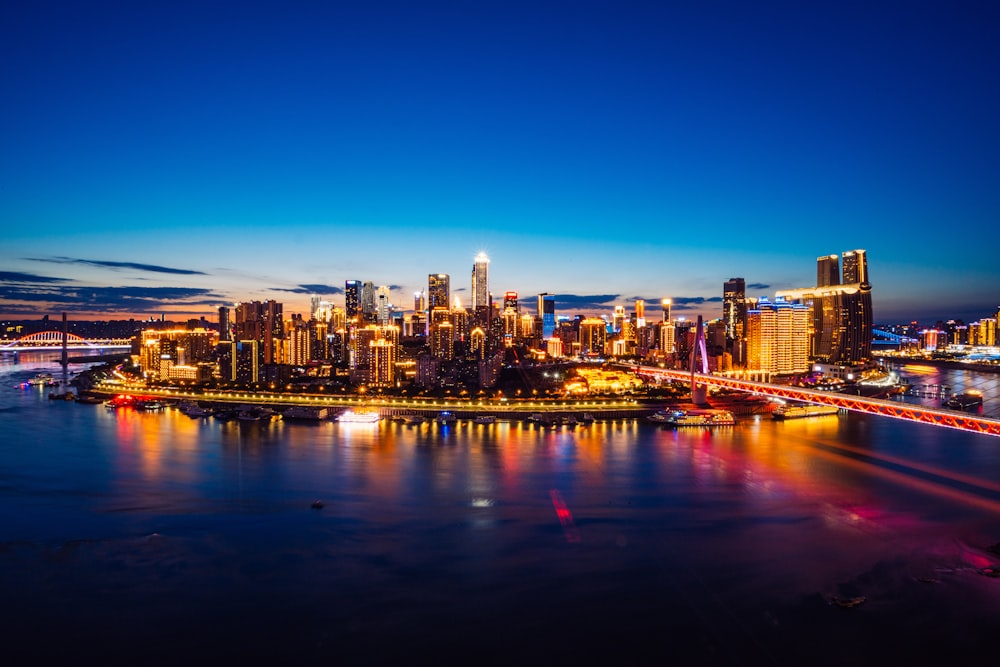 a city skyline at night with a bridge in the foreground