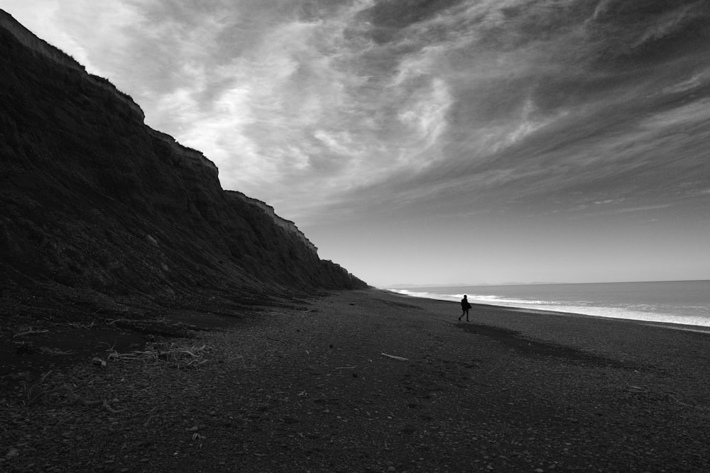 a person standing on a beach next to a cliff