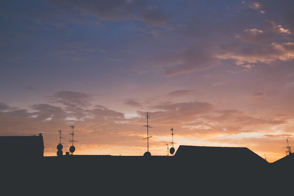 the sun is setting over a rooftop with several antennas