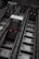 View of an industrial elevator system, featuring large mechanical components and rail tracks with red indicator lights. The perspective is from the bottom looking up, creating a sense of height and depth.