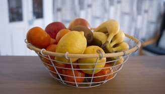 A cheerful basket overflowing with fresh bananas and other fruits on a wooden table.