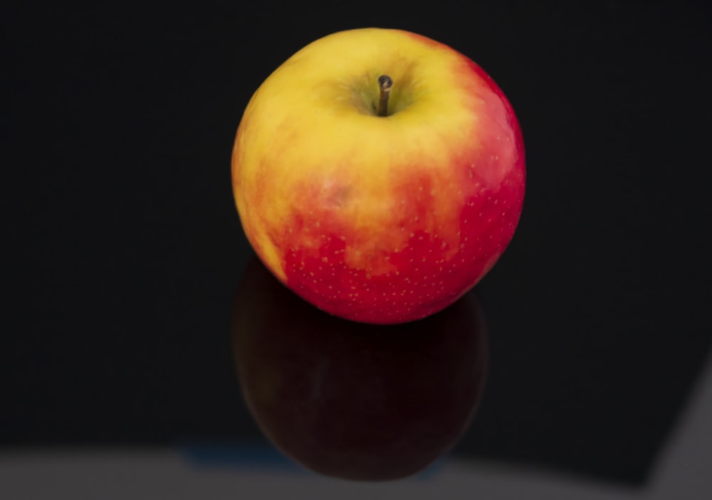 a red and yellow apple sitting on top of a table