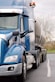 a blue semi truck driving down a street