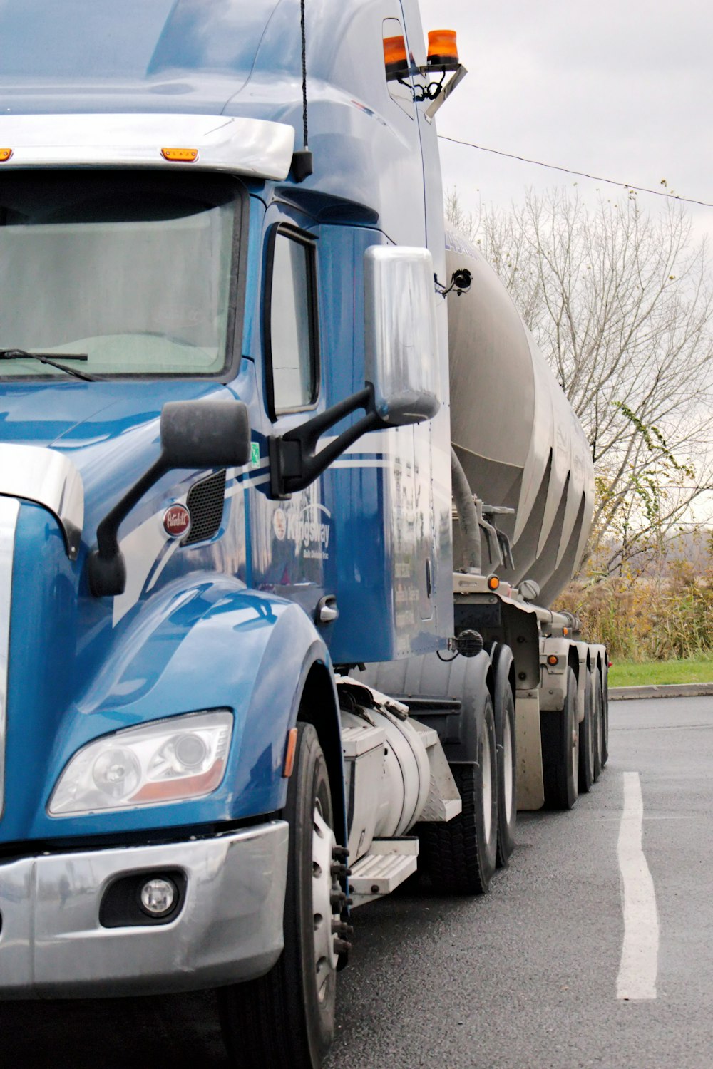 a blue semi truck driving down a street