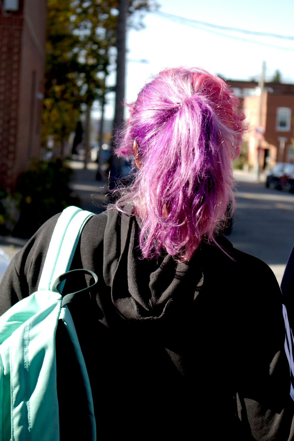 a woman with pink hair walking down the street