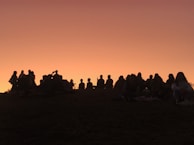 A sunset silhouette of the group standing on a hill, symbolizing hope and resilience for the future.