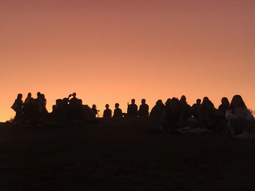 A group of smiling friends sharing a quiet moment during a sunset sound healing session.