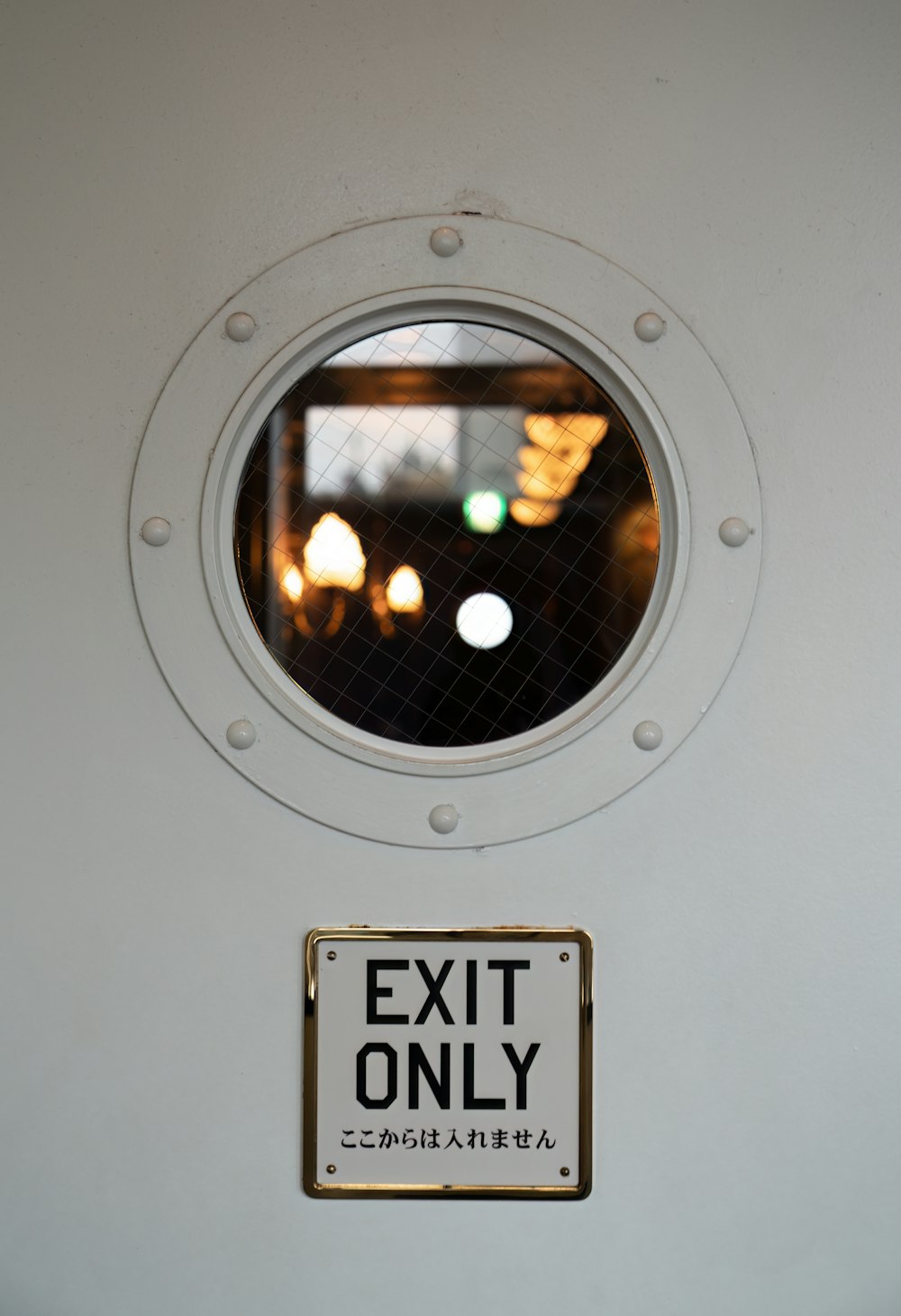 a porthole window with a sign that says exit only