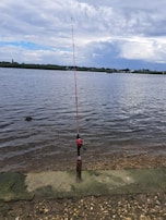 A serene view of the private trophy bass pond with fishing gear ready by the shore.