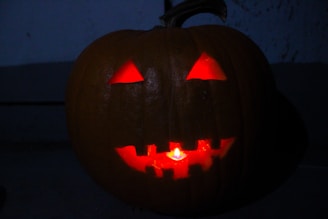 A close-up of a carved jack-o'-lantern with a flickering candle inside.
