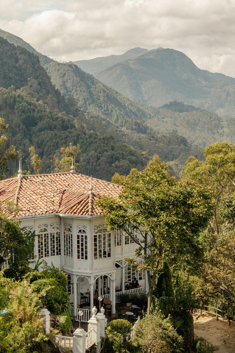 a large white house surrounded by trees and mountains