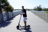Customer riding a hypertech scooter along a beachside boardwalk.