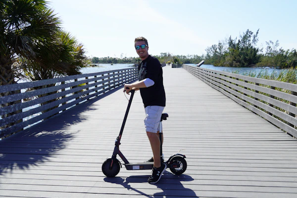 A sleek electric skateboard gliding smoothly over a sunlit boardwalk near the water.